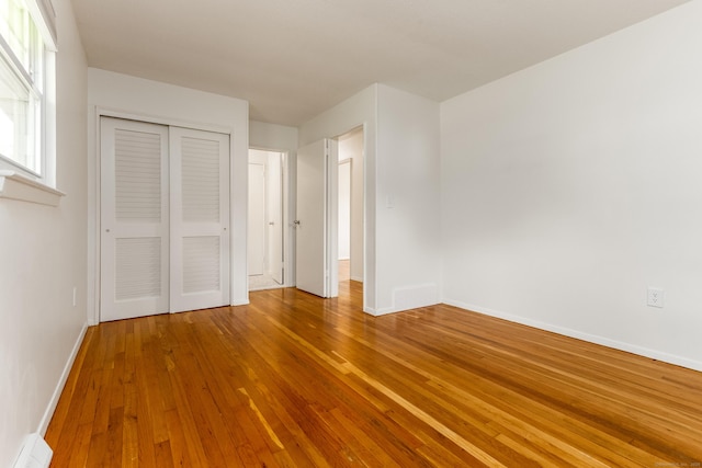 unfurnished bedroom featuring baseboards, a closet, and hardwood / wood-style floors