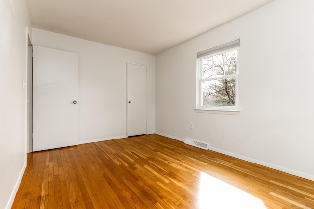 unfurnished bedroom featuring wood-type flooring, baseboards, and visible vents