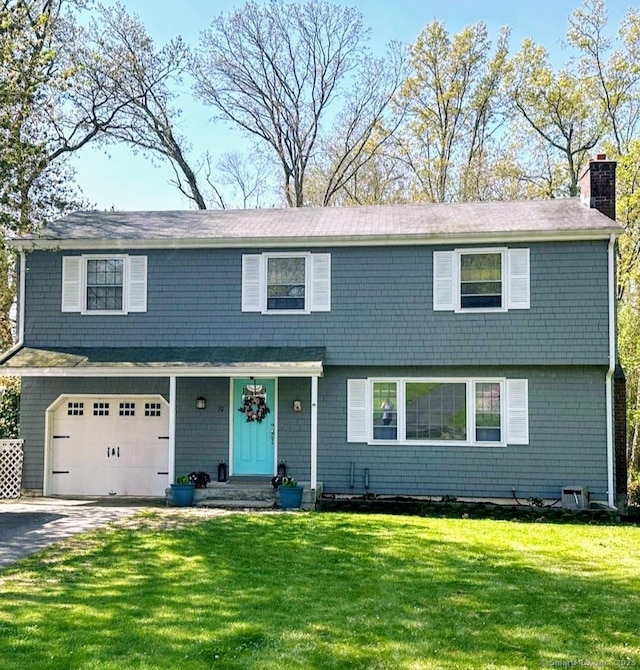view of front of house with a garage, a chimney, a front lawn, and driveway