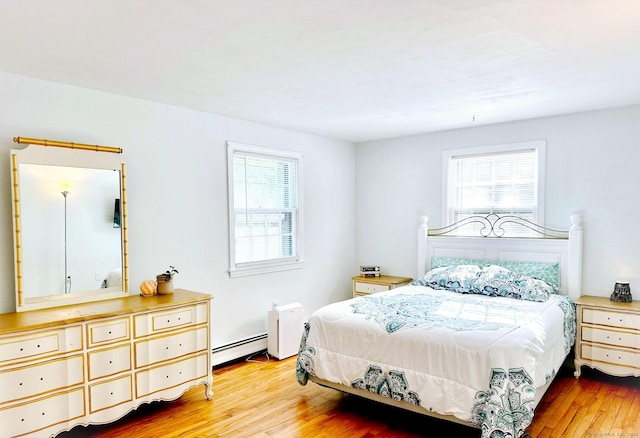 bedroom featuring a baseboard heating unit and wood finished floors