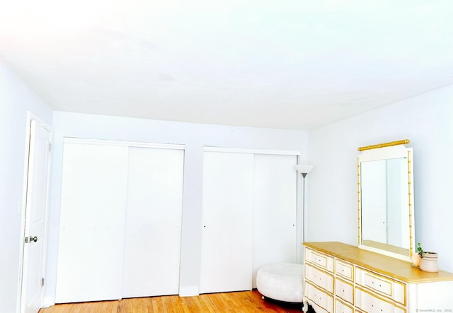 bedroom with two closets and light wood finished floors