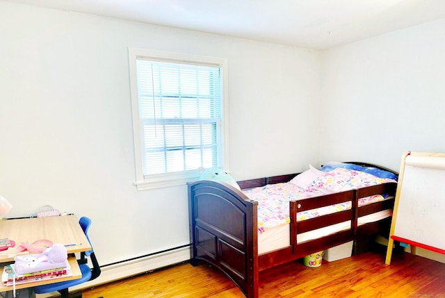 bedroom featuring light wood-style flooring, a baseboard radiator, and baseboards