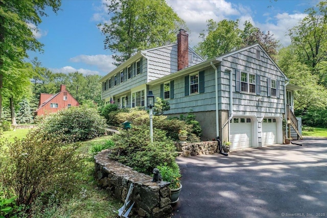 12 Winding Brook Ln, Redding, CT 06896 - view of home's exterior featuring a chimney, asphalt driveway, a garage, and stairs