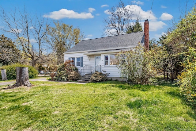 view of front of home with a chimney, a front yard, and roof with shingles