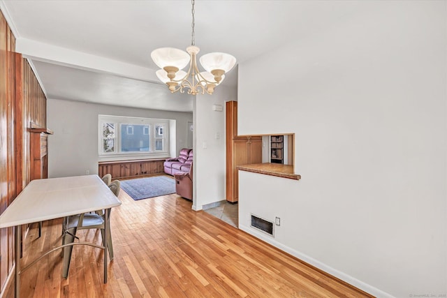 dining space with visible vents, baseboards, light wood finished floors, a fireplace, and a notable chandelier