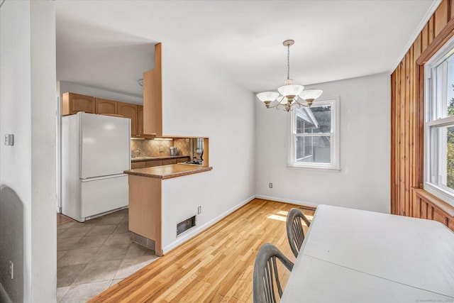 dining space featuring baseboards, visible vents, a notable chandelier, and light wood finished floors