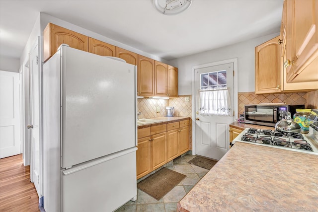 kitchen with range, black microwave, light countertops, freestanding refrigerator, and backsplash