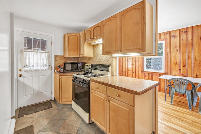 kitchen featuring gas stove, black microwave, a wealth of natural light, and decorative backsplash