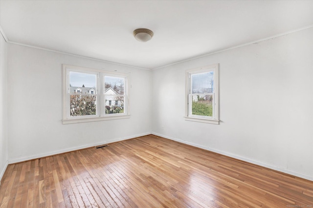 unfurnished room with visible vents, ornamental molding, a healthy amount of sunlight, and light wood-style flooring