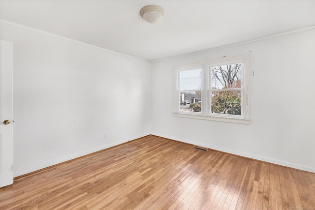 empty room with crown molding, visible vents, baseboards, and light wood-style floors