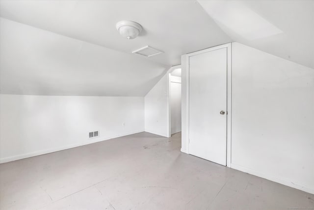 bonus room with concrete floors, vaulted ceiling, attic access, baseboards, and visible vents