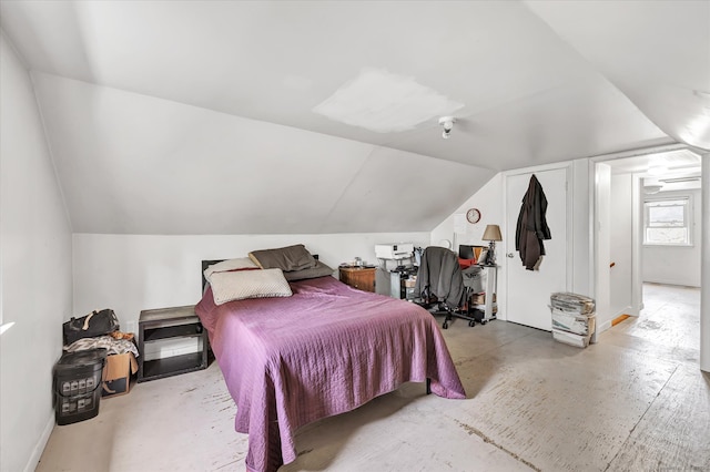 bedroom with concrete flooring, vaulted ceiling, and baseboards