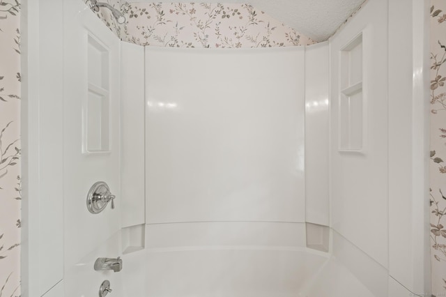 bathroom with a textured ceiling and bathtub / shower combination