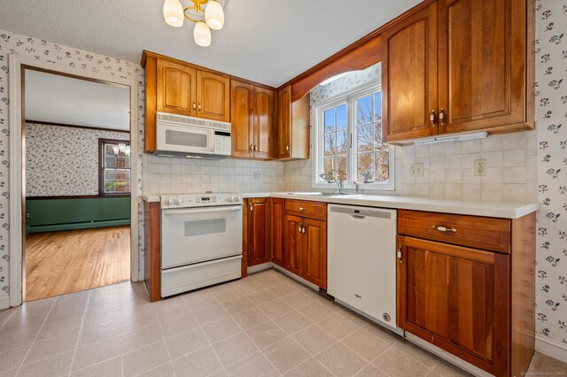 kitchen featuring baseboard heating, light countertops, wallpapered walls, and white appliances