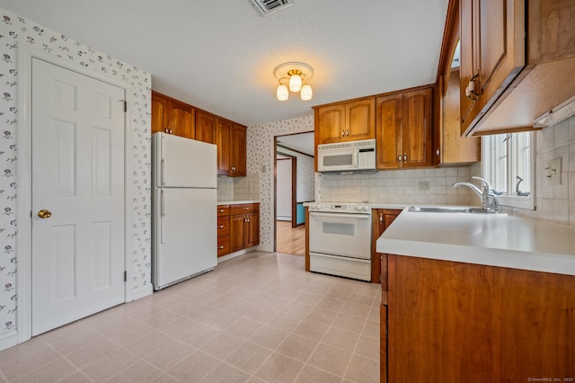 kitchen featuring a sink, brown cabinets, white appliances, and light countertops