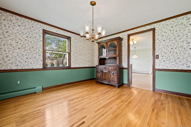 unfurnished dining area with a notable chandelier, light wood-style floors, wallpapered walls, baseboards, and ornamental molding