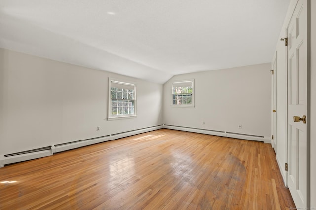 interior space with a baseboard heating unit, lofted ceiling, and light wood-type flooring