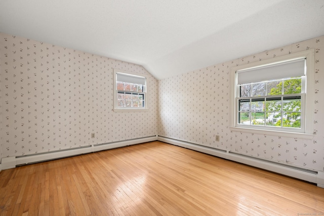 interior space featuring wood-type flooring, wallpapered walls, lofted ceiling, and a baseboard radiator