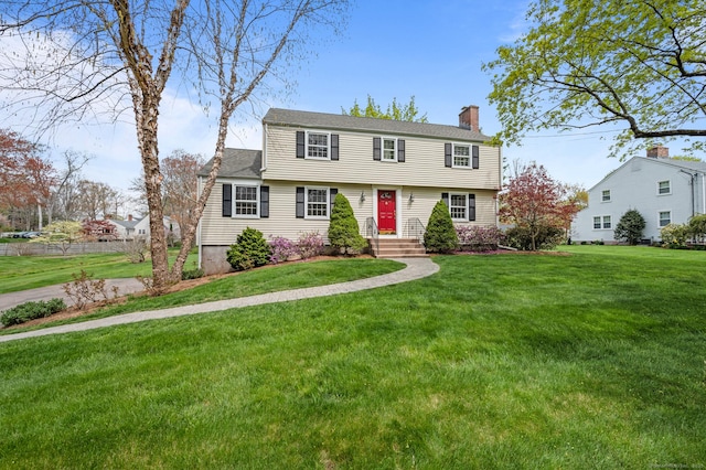 colonial home with a chimney and a front yard