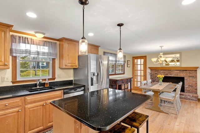 kitchen featuring a sink, stainless steel fridge with ice dispenser, a chandelier, light wood finished floors, and a kitchen island