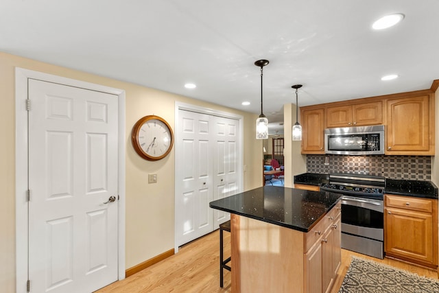 kitchen featuring stainless steel appliances, light wood-type flooring, a center island, decorative backsplash, and dark stone countertops
