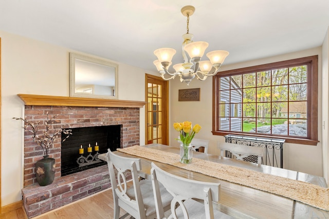 dining space with a chandelier, wood finished floors, and a fireplace