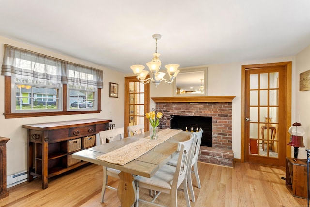dining area featuring a chandelier, light wood finished floors, baseboard heating, and a fireplace