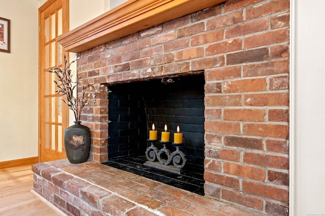 detailed view of baseboards, wood finished floors, and a fireplace