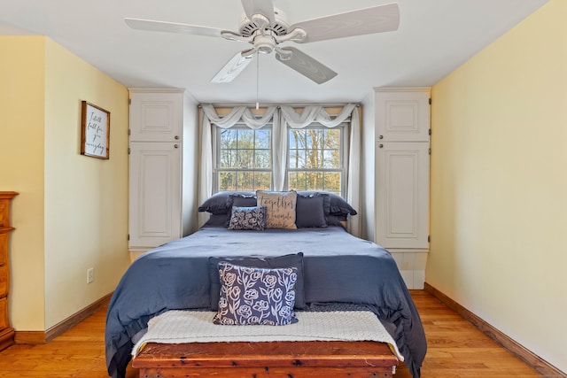 bedroom with light wood finished floors, baseboards, and ceiling fan