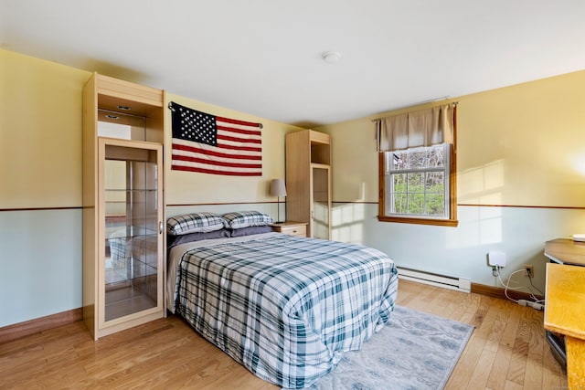 bedroom featuring baseboard heating, baseboards, and hardwood / wood-style flooring