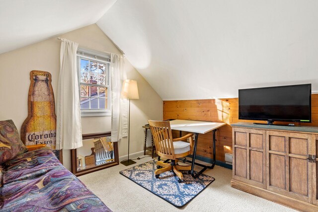 carpeted home office featuring vaulted ceiling, wooden walls, and baseboards