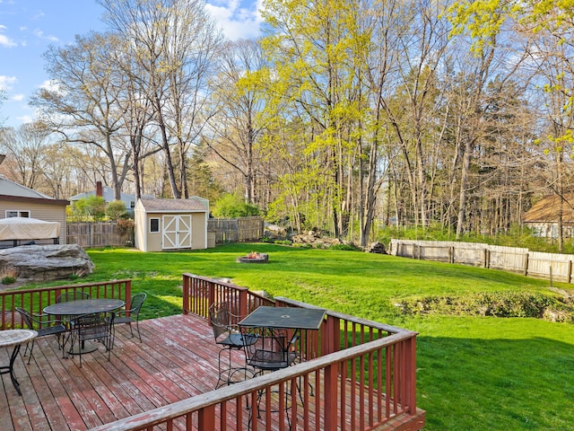 wooden terrace featuring outdoor dining space, a storage shed, and an outbuilding