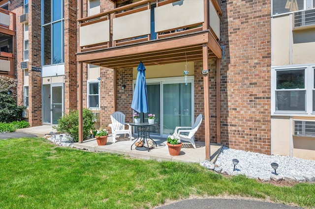 exterior space featuring a lawn, a balcony, a patio, and brick siding