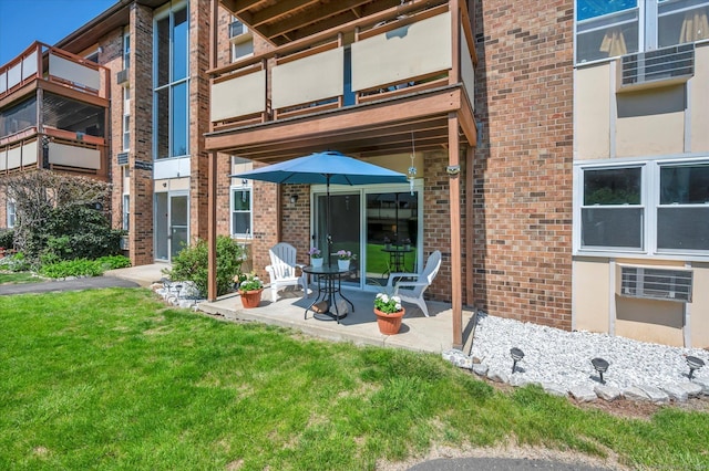 back of house with a yard, a balcony, a patio, and brick siding