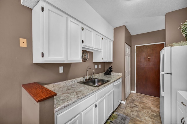 kitchen with baseboards, freestanding refrigerator, dishwasher, a sink, and white cabinetry