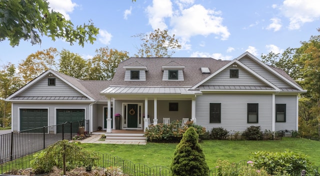 new england style home featuring a shingled roof, an attached garage, a front yard, a standing seam roof, and covered porch