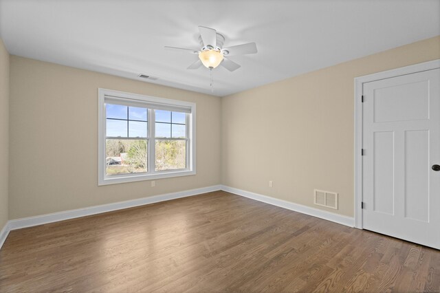 empty room featuring baseboards, ceiling fan, wood finished floors, and visible vents