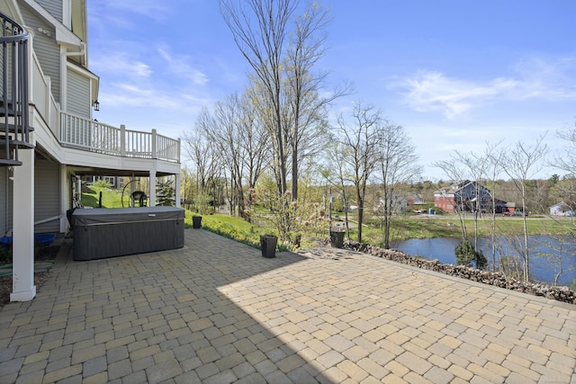 view of patio / terrace featuring a hot tub and a water view