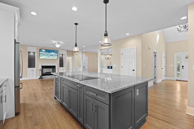 kitchen featuring a multi sided fireplace, open floor plan, gray cabinets, and light wood finished floors