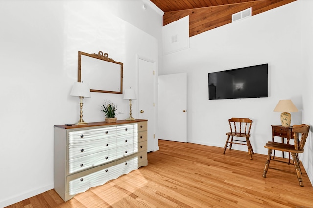 living area featuring light wood-type flooring, a towering ceiling, wooden ceiling, baseboards, and visible vents