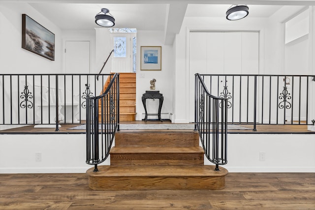 staircase with a baseboard radiator, baseboards, and wood finished floors