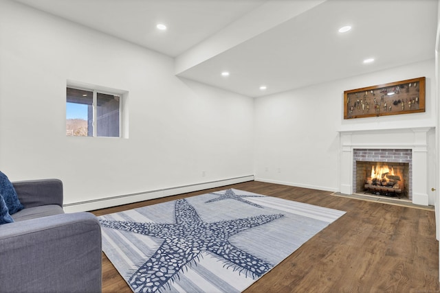 living area with a fireplace with flush hearth, a baseboard radiator, wood finished floors, and recessed lighting