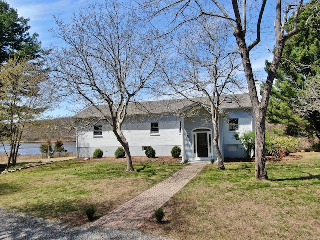 view of front of home with a front lawn and a water view
