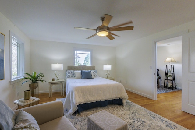 bedroom with light wood-style floors, a ceiling fan, baseboards, and multiple windows