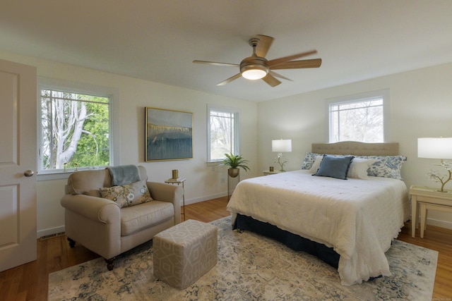 bedroom featuring a ceiling fan, multiple windows, and wood finished floors
