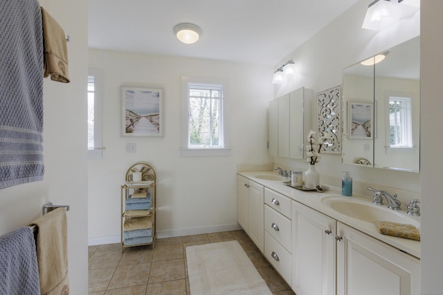 bathroom with double vanity, a sink, tile patterned floors, and baseboards