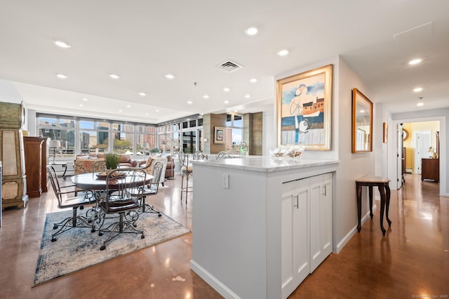 kitchen featuring visible vents, recessed lighting, finished concrete flooring, white cabinets, and baseboards