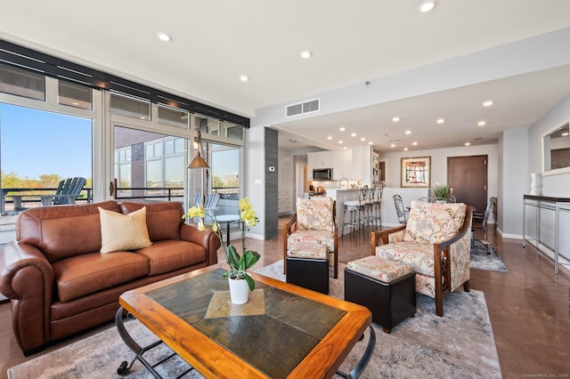 living room with finished concrete flooring, visible vents, baseboards, and recessed lighting