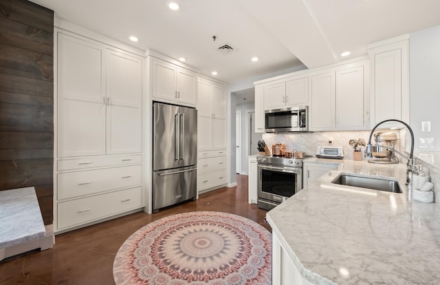 kitchen with a sink, stainless steel appliances, light stone counters, visible vents, and recessed lighting
