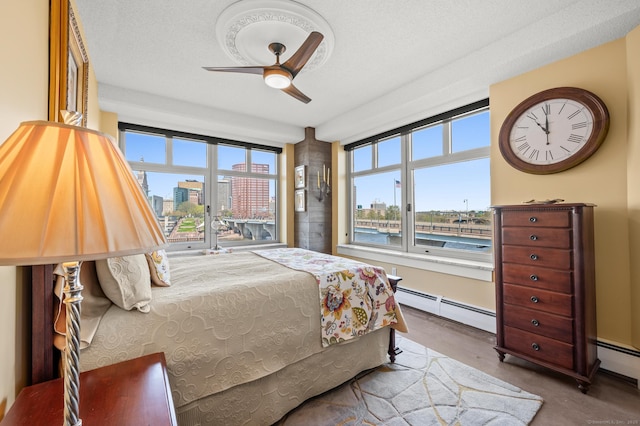 bedroom with a city view, ceiling fan, and a baseboard heating unit